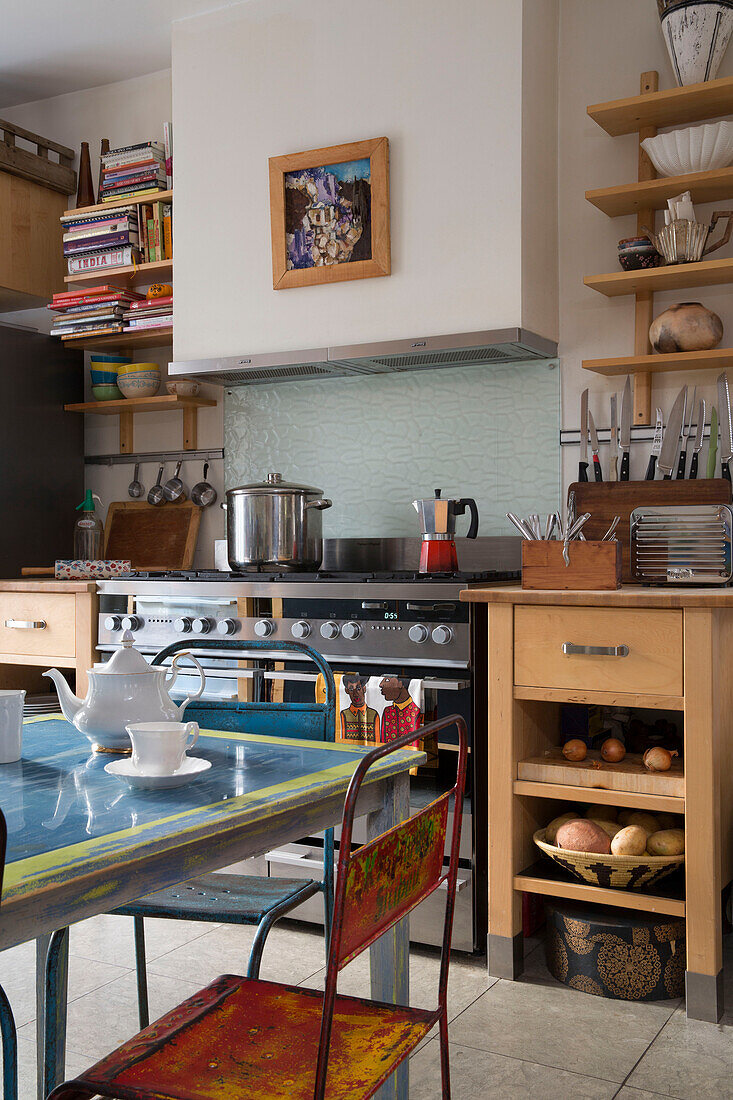 Kochtopf auf dem Kochfeld mit Büchern auf einem Regal in einer Londoner Küche, England, UK