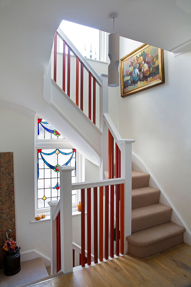 Rotes Geländer im Treppenhaus mit Teppichboden und Glasmalerei in einem Londoner Haus England UK