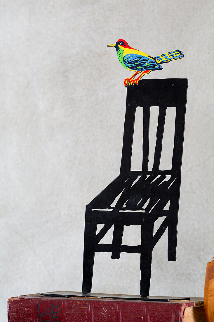 Bird perched on black chair in London home England UK