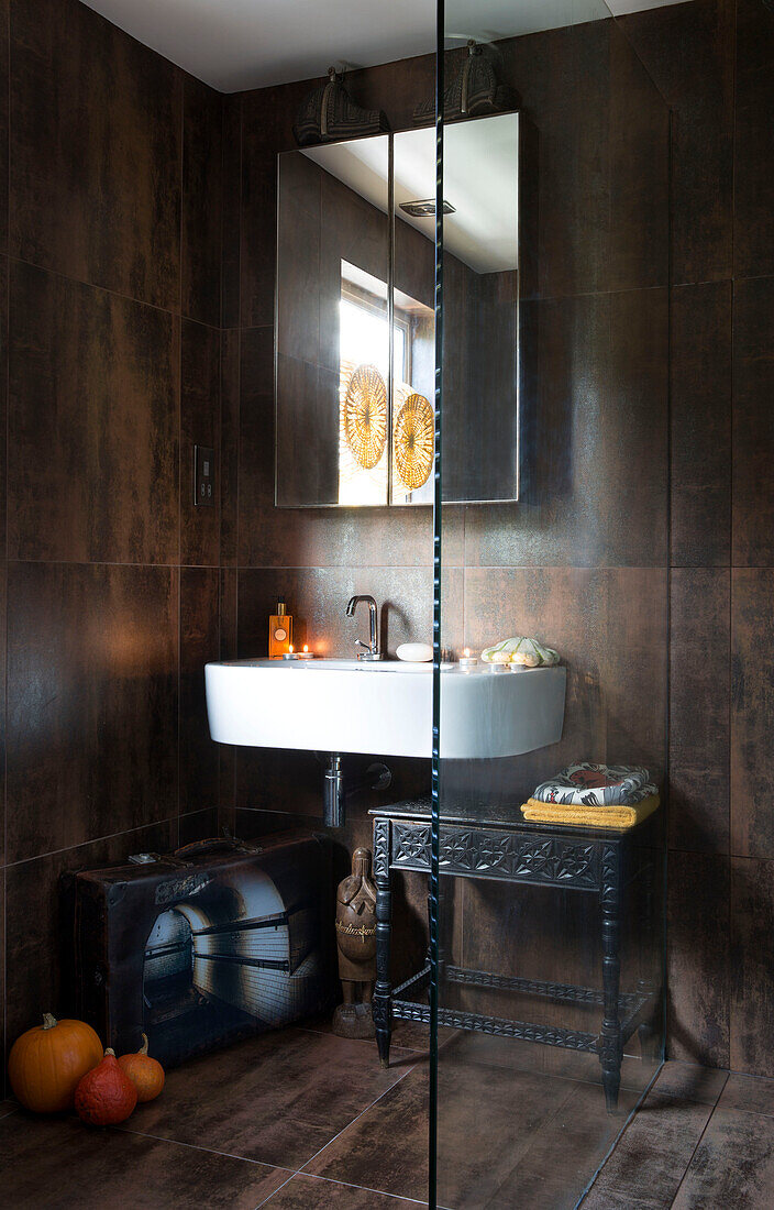 Spiegel über dem Waschbecken mit geschnitztem Beistelltisch in einem Haus in London, England UK