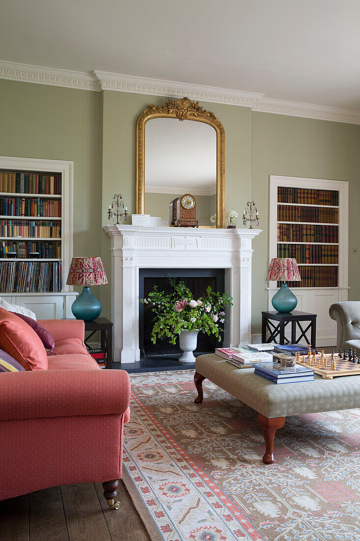 Pink sofa with recessed bookcases and ottoman with chess set in Grade II listed Georgian country house in Shropshire England UK