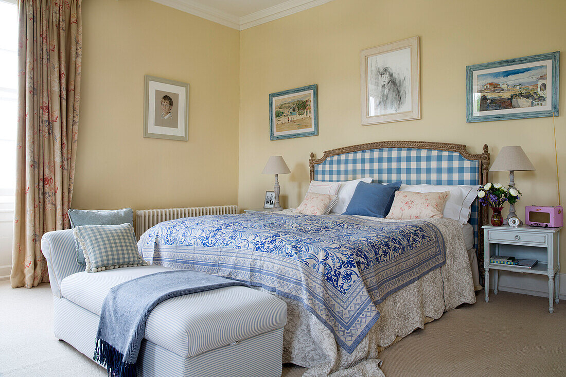 Checked headboard and blue patterned bedspread on double bed in Grade II listed Georgian country house in Shropshire England UK