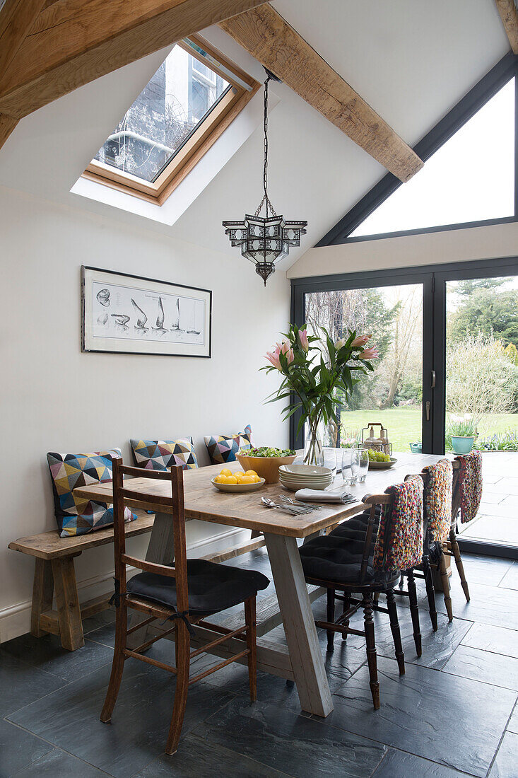 Dining table and chairs in beamed Sussex kitchen extension England UK