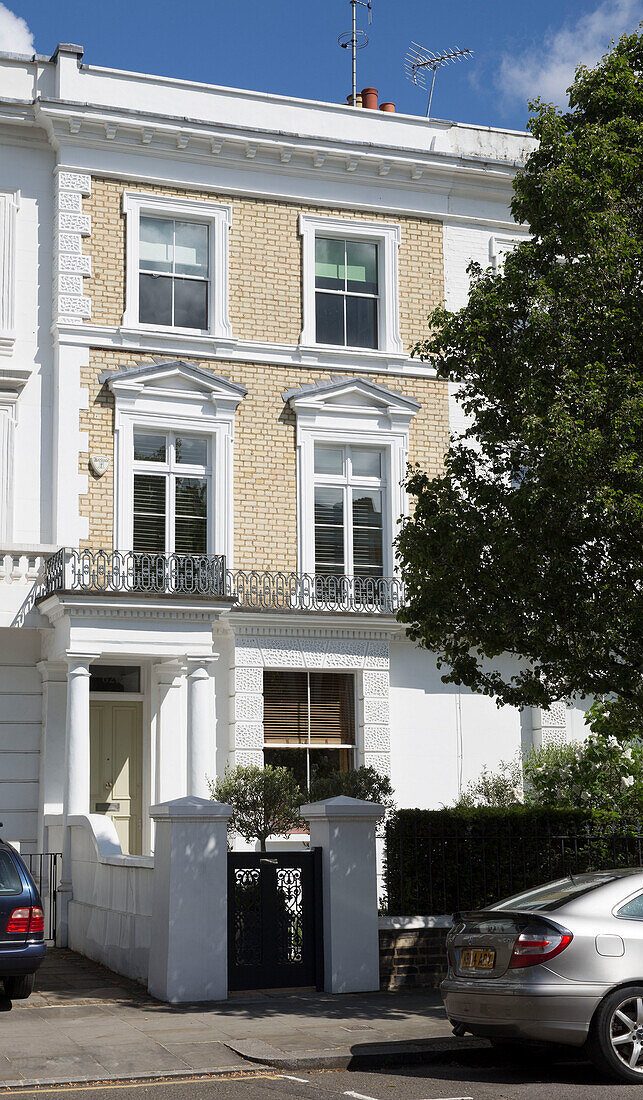 Autos, die vor einem dreistöckigen Londoner Stadthaus mit weißem Anstrich geparkt sind England UK
