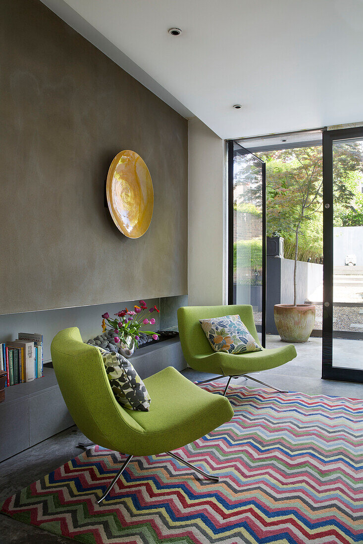 Ein Paar lindgrüne Sessel mit Zickzack-Teppich in einem modernen Londoner Stadthaus England UK