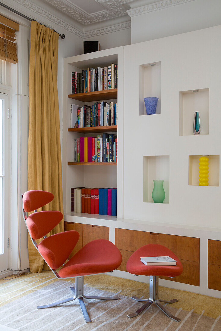 Roter Sessel und Fußhocker mit Nischenregal und Bücherregal in einem Londoner Stadthaus England UK