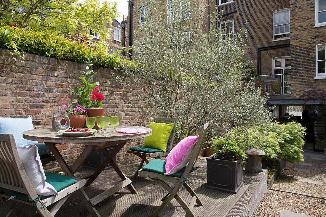 Outdoors table and chairs on decking in garden exterior of London townhouse England UK