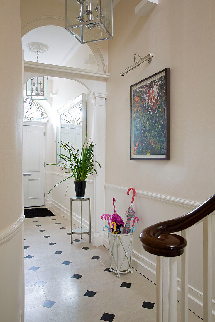 Houseplant on stand with artwork in tiled hallway of London townhouse England UK