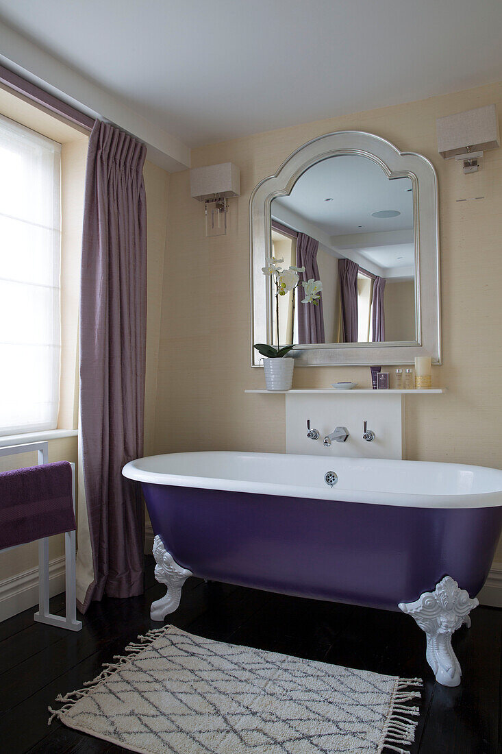 Lila freistehende Badewanne mit klassischem Spiegel in einem Londoner Stadthaus, England, UK