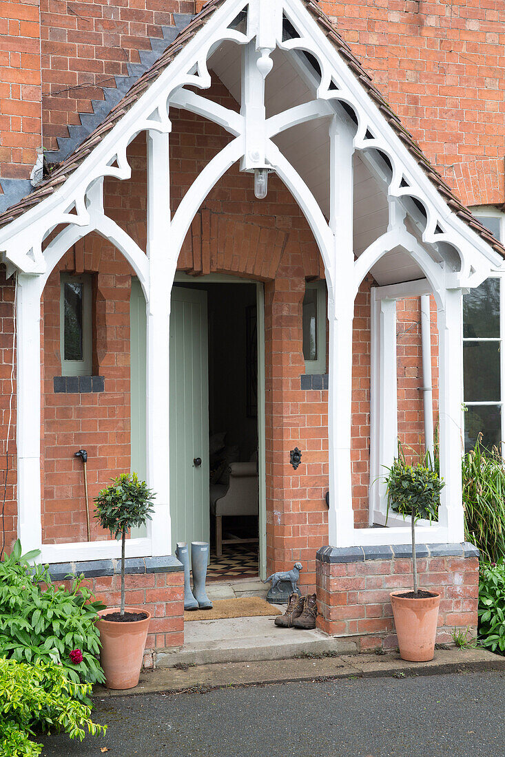 Wellington boots at open front door in brick porch of Worcestershire home England UK