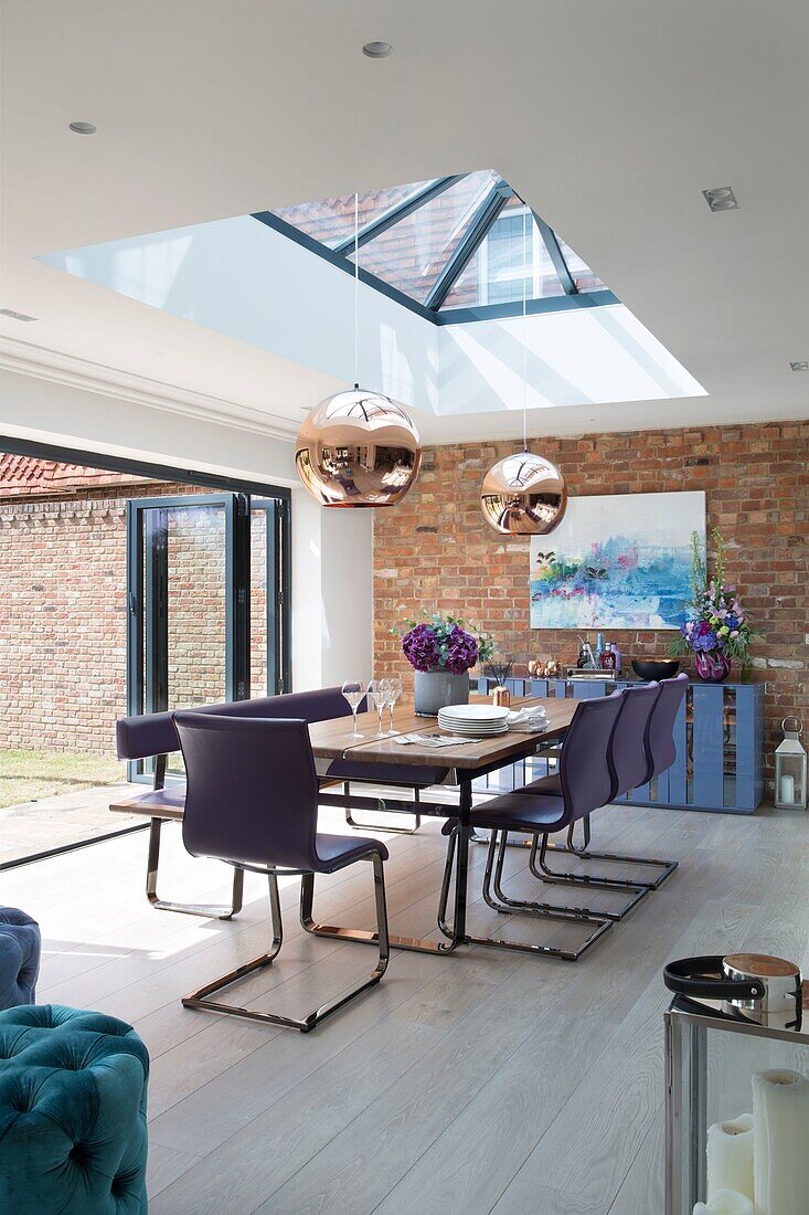 Moderner Anbau mit freiliegender Ziegelwand und Oberlicht-Pendelleuchten in einem Haus in Sussex England UK