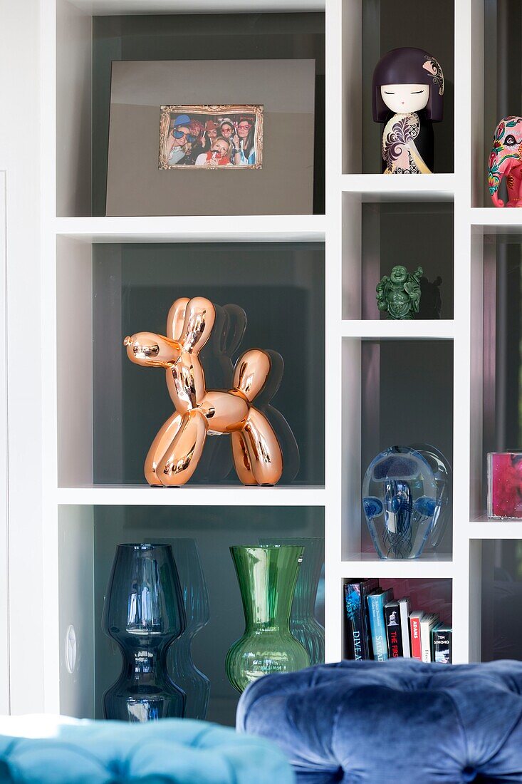 Glasornamente mit Kupferhund auf einem Regal im Wohnzimmer in Sussex, England UK