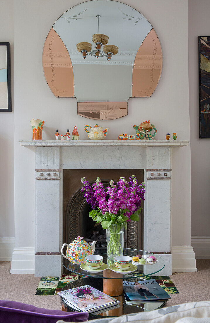 Schnittblumen auf Couchtisch mit Vintage-Spiegel über dem Kamin im Wohnzimmer eines Londoner Stadthauses UK