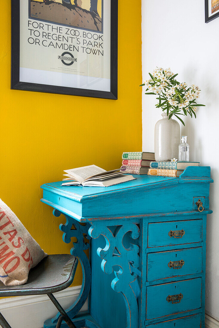 Türkisfarbener Schreibtisch und gelbe Wand mit gerahmtem Poster in einem Haus in Yorkshire, England, Vereinigtes Königreich