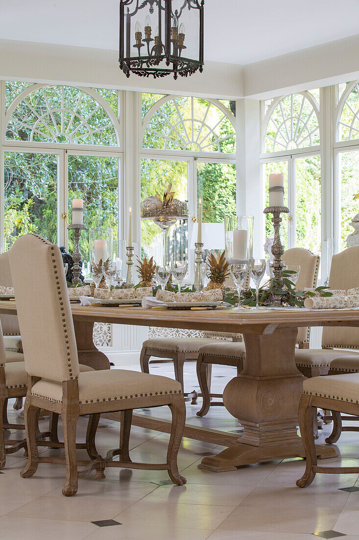 Cream dining chairs at table in Kent conservatory with fanlight windows England UK