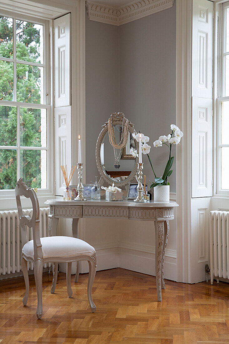 Orchid on dressing table with chair and parquet floor at windows in Kent country house England UK
