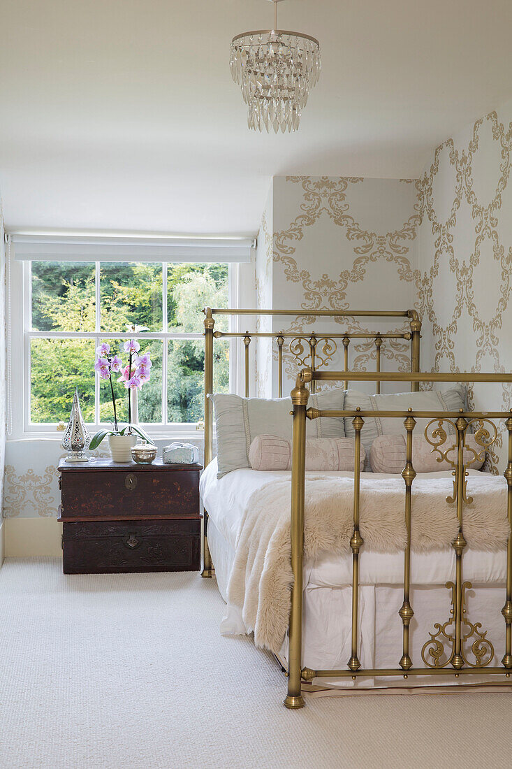 Antique brass bed with travelling chest at window in Kent country house England UK