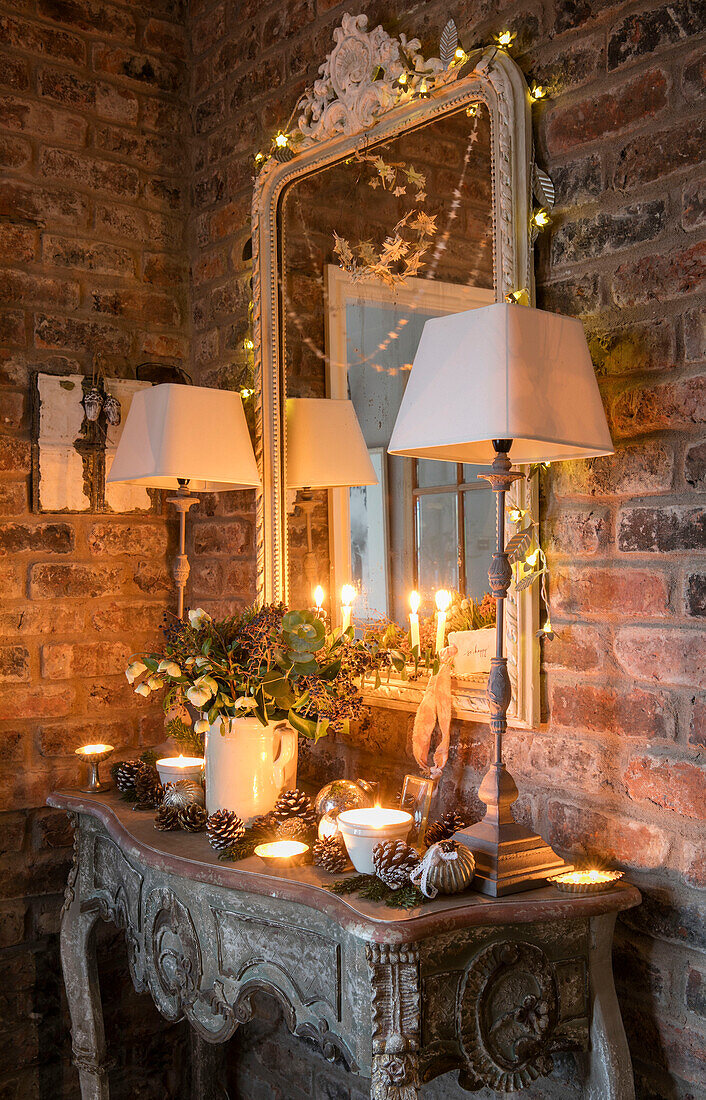 Lampenpaar und Spiegel mit brennenden Kerzen und Tannenzapfen in einem Haus in Cheshire UK