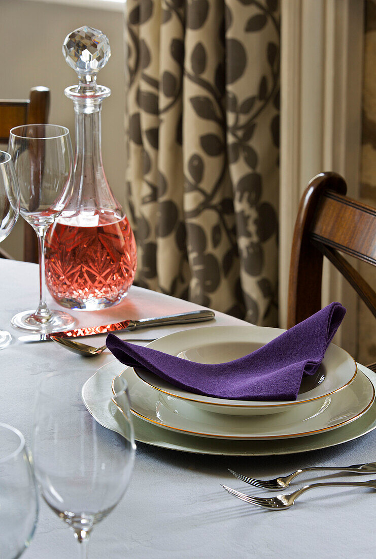 Purple napkin in place setting with decanter of rose in Gloucestershire farmhouse England UK
