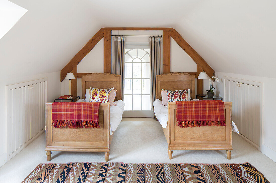 Wooden twin beds with checked blankets in Gloucestershire farmhouse England UK