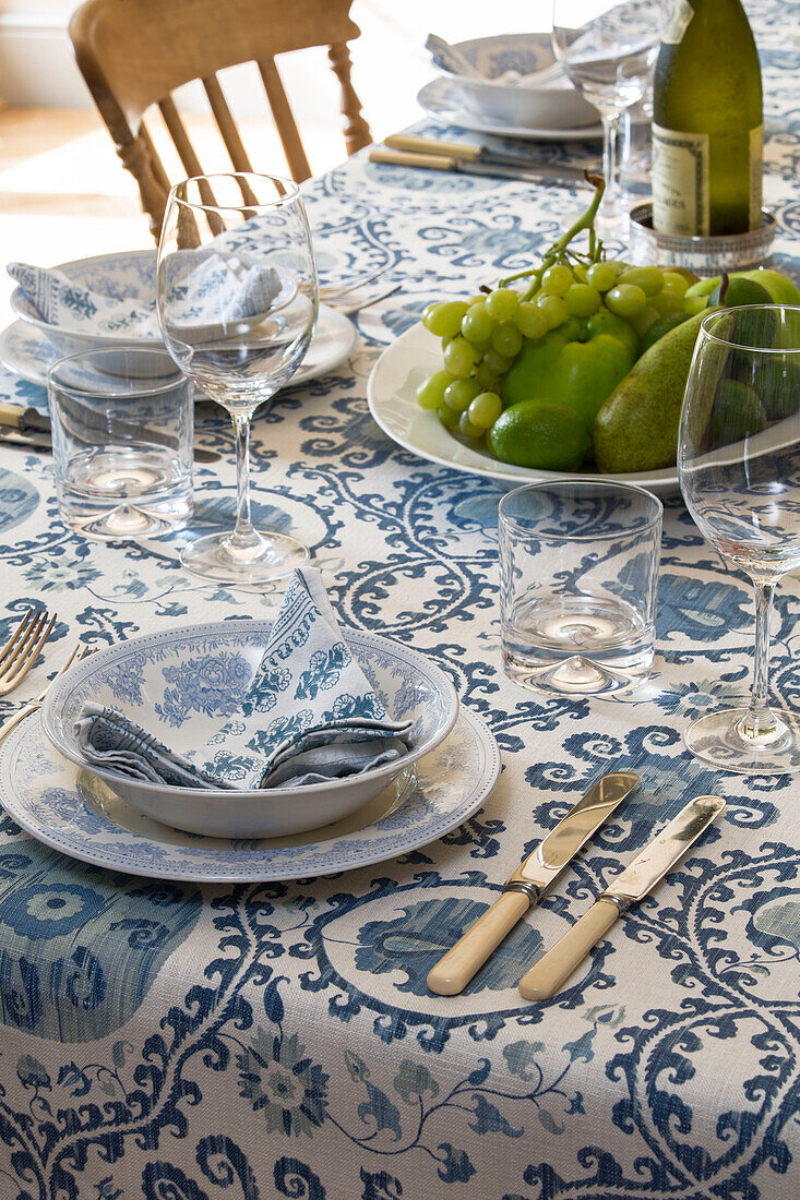 Blue and white napkin in bowl with cutlery and grapes on dining table in Gloucestershire cottage UK