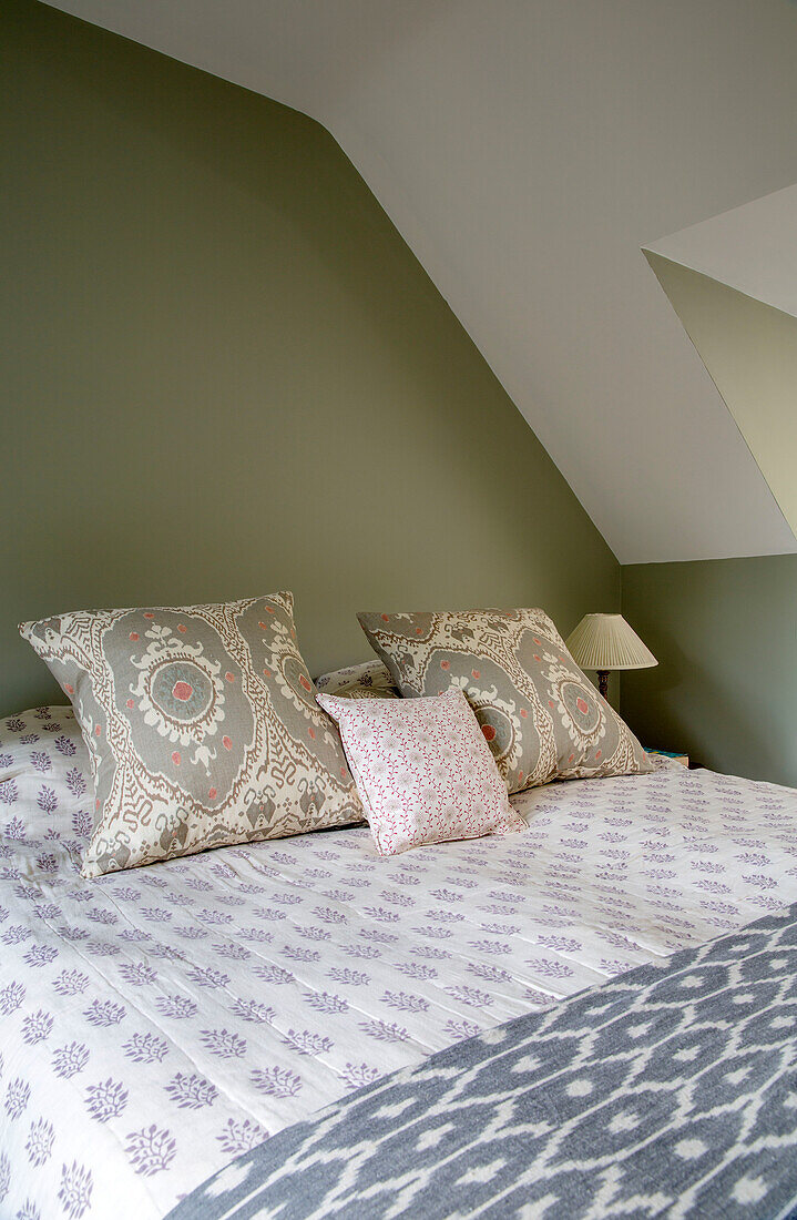 Doppelbett mit kontrastierenden Stoffmustern in einem Schlafzimmer in Gloucestershire UK