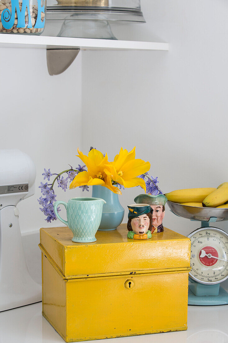 Schnittblumen und Tassen auf einem gelben Schrank in der Küche von Brighouse West Yorkshire UK