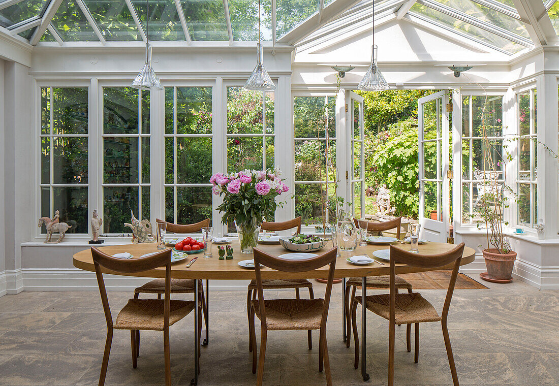 Wooden dining table and chairs in conservatory extension of London townhouse UK
