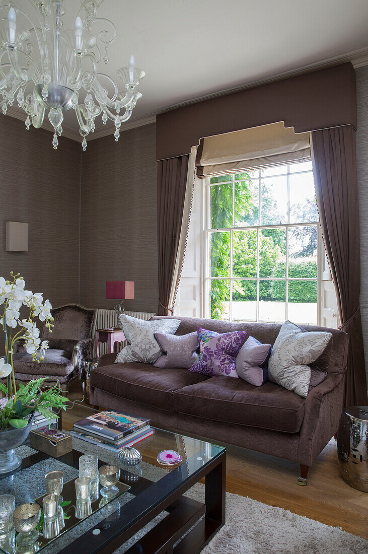 Kissen auf braunem Sofa mit gläsernem Couchtisch in einem freistehenden Landhaus in Sussex UK
