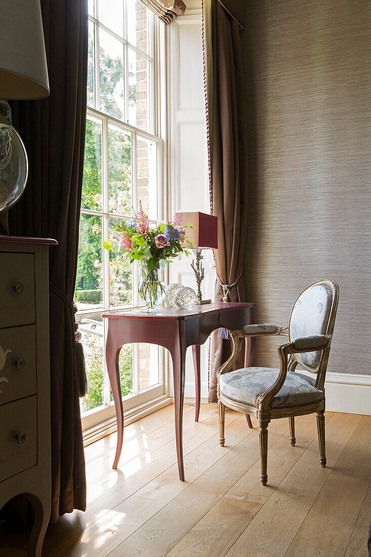 Cut flowers on desk at window with chair in detached Sussex country house UK