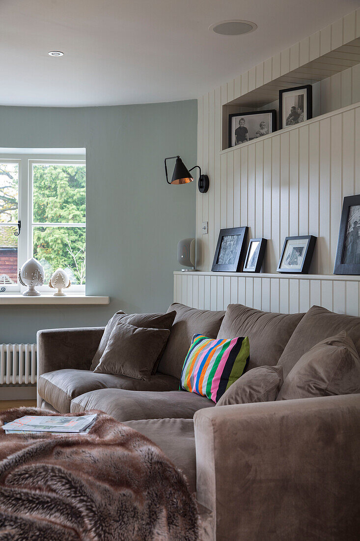 Hellbraunes Sofa mit schwarz-weiß gerahmten Fotos in einem umgebauten Herrenhaus in Kent, Großbritannien