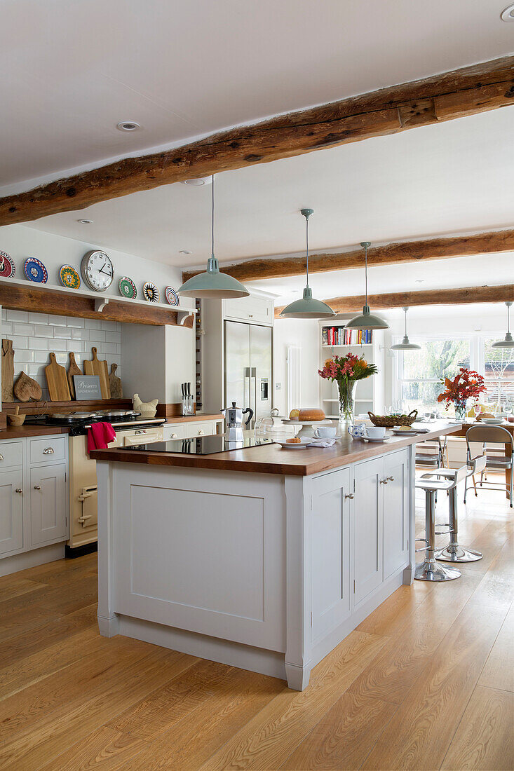 Pendelleuchten über einer weißen Kücheninsel in der offenen Küche eines umgebauten Gasthauses in Kent UK