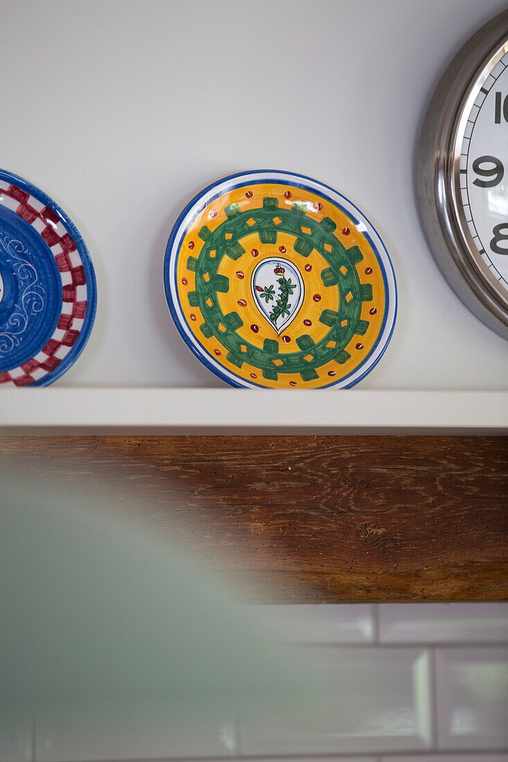 Dekorative Teller und Uhr auf Küchenregal in umgebautem Oast House Kent UK