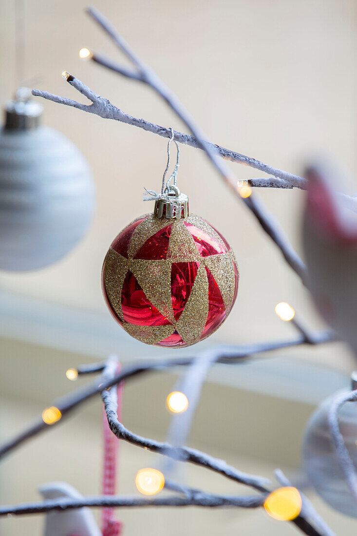 Red and gold bauble on twig decoration in London townhouse UK