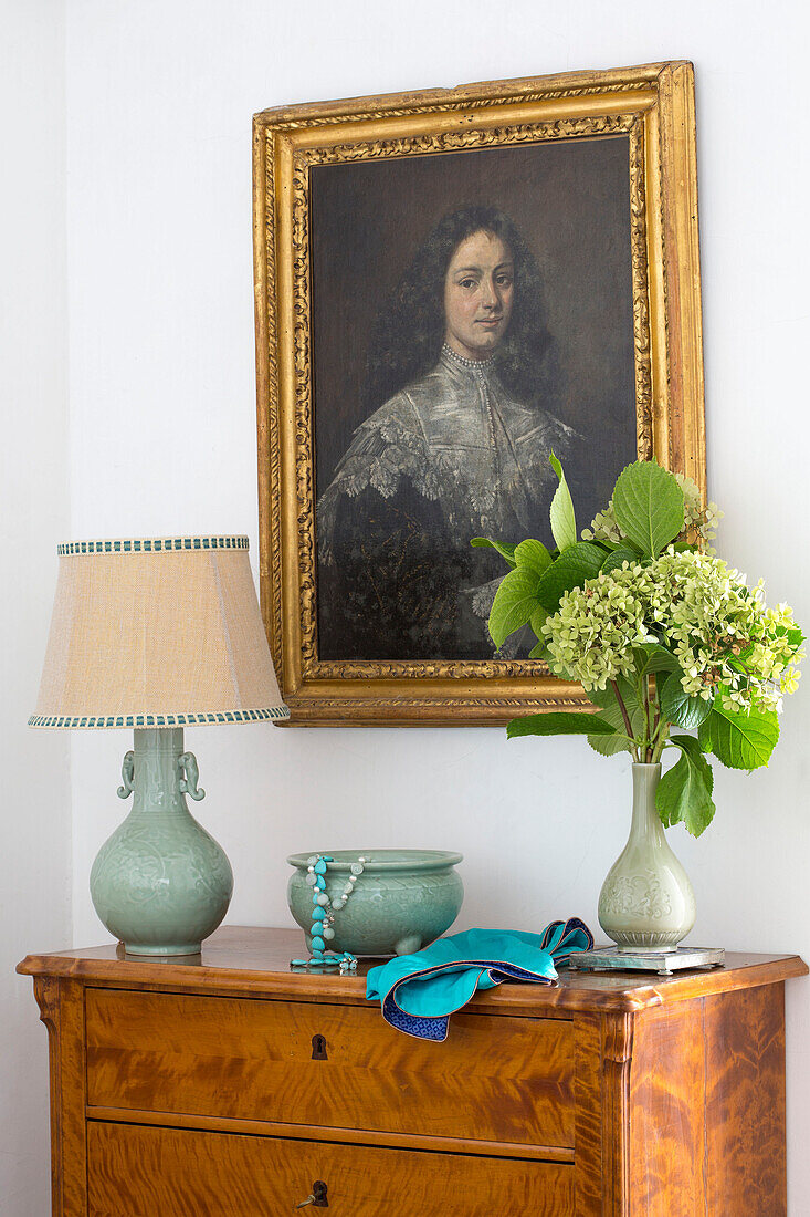 Vergoldetes gerahmtes Porträt über einer hölzernen Kommode mit Lampe und Blumen in einer Villa an der Küste von Amalfi, Italien