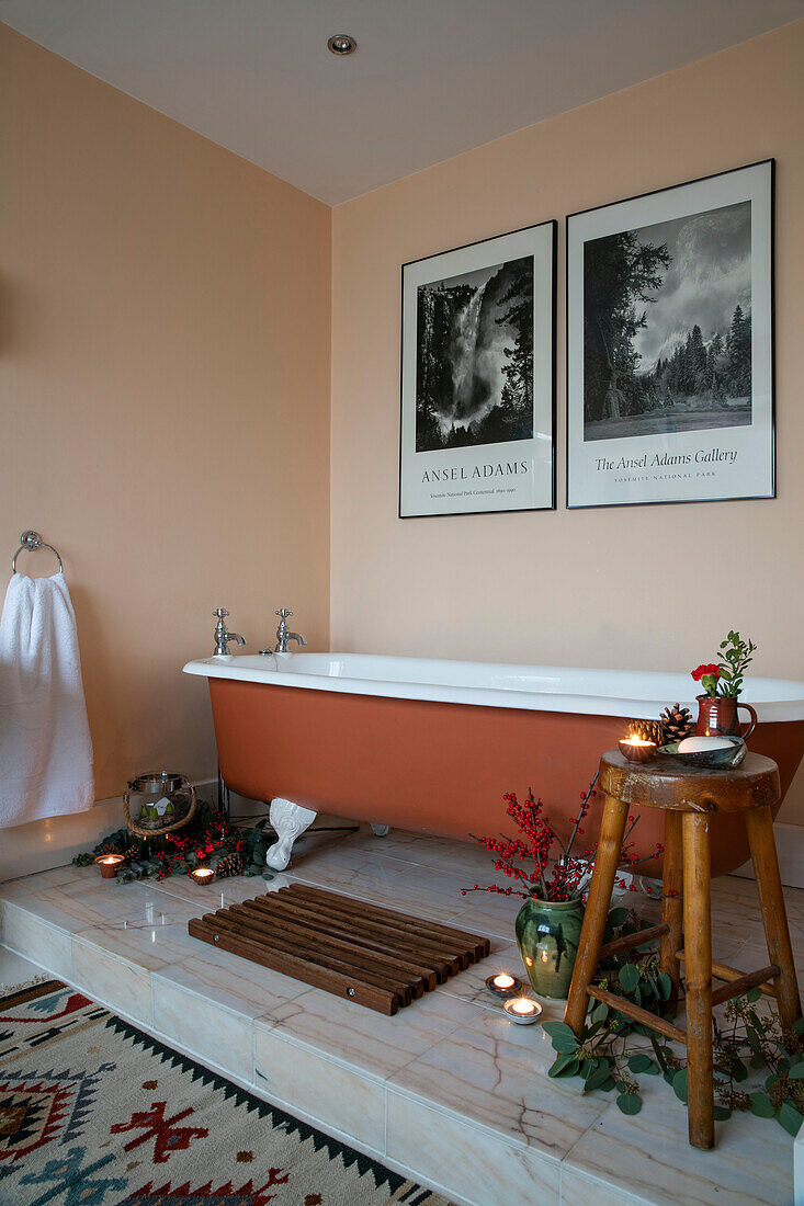 Braune freistehende Badewanne mit Schwarz-Weiß-Drucken und Weihnachtsdekoration in einem Haus in Berkshire, England