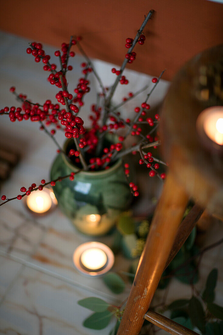 Red berries and lit tealights with wooden stool in Berkshire home UK