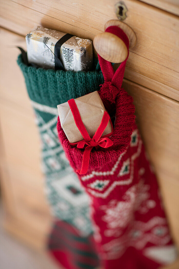 Weihnachtsstrümpfe hängen mit Geschenken am Griff einer Holzschublade in einem Haus in Berkshire, UK