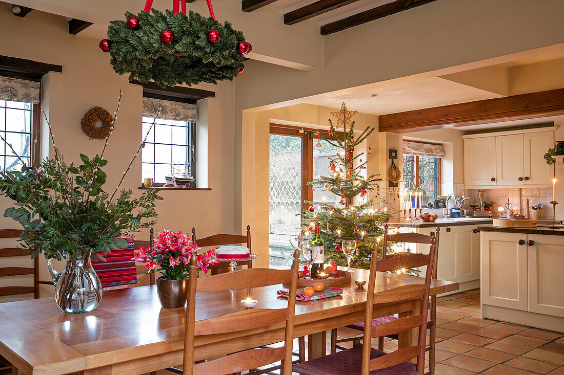 Blattarrangement auf einem hölzernen Esstisch mit Weihnachtsbaum in einem Haus in Berkshire UK