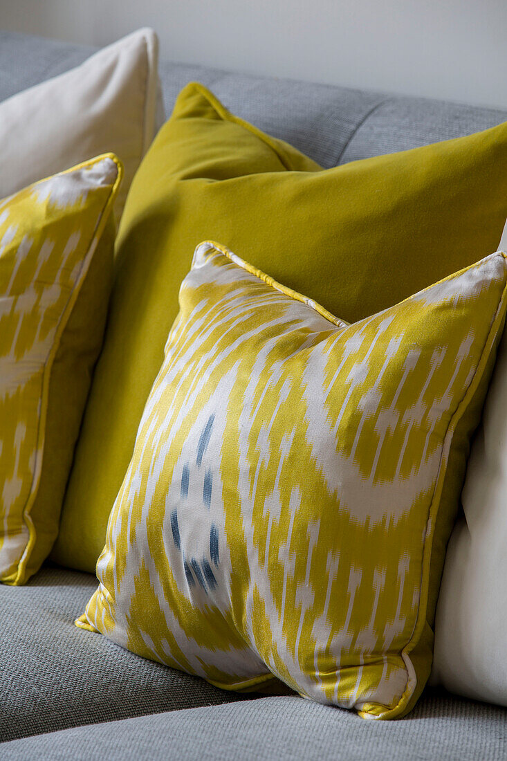 Gelbe Kissen auf grauem Sofa in einem Londoner Stadthaus UK