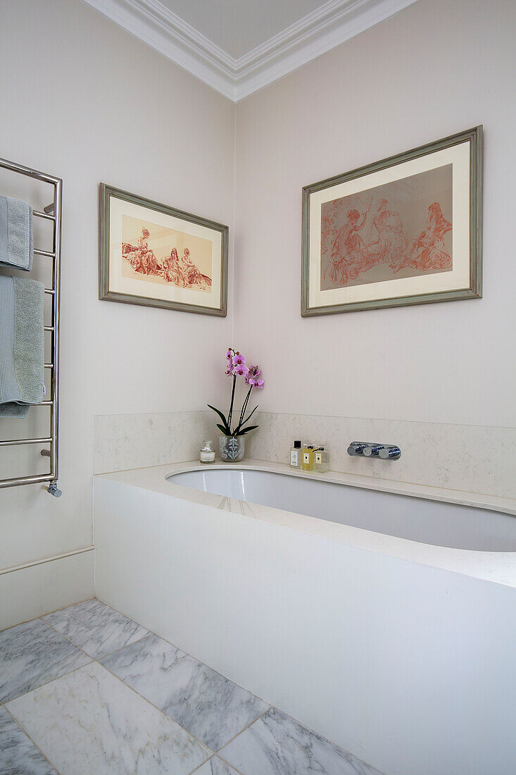 Gerahmtes Kunstwerk über einer Orchidee und Toilettenartikeln auf einem Badewannenrand in einem Londoner Stadthaus UK