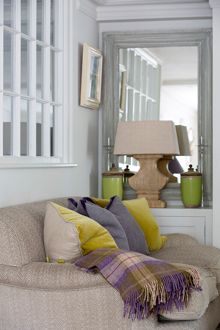 Sofa and cushions with purple checked blanket in West Sussex home