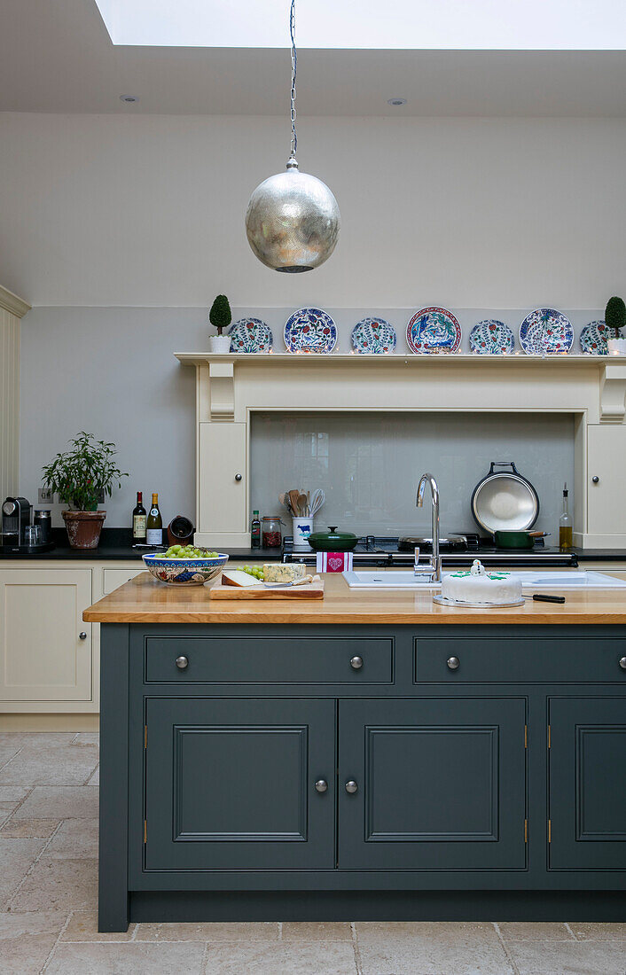 Silberne Hängelampe über einer aquamarinfarbenen Werkbank in einer Bauernhausküche in Dorset UK