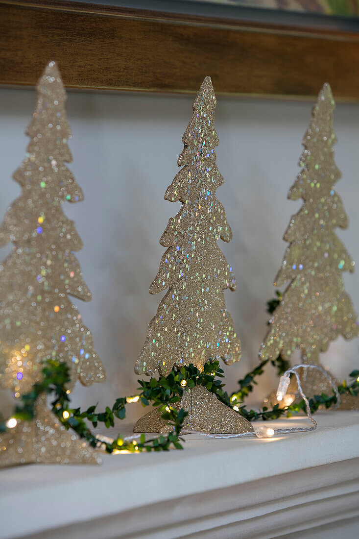Three gold Christmas trees with garland of fairylights in Dorset farmhouse UK