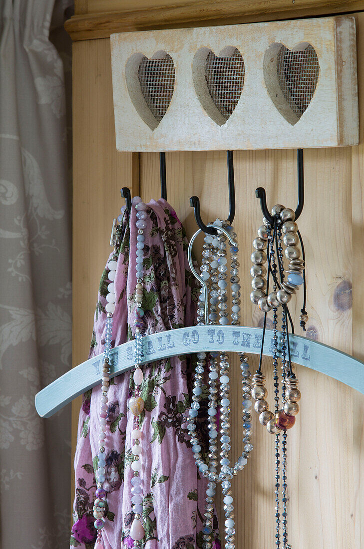 Rosa Schal und Kleiderbügel mit Perlenketten am Herzhaken in Alford, Surrey UK