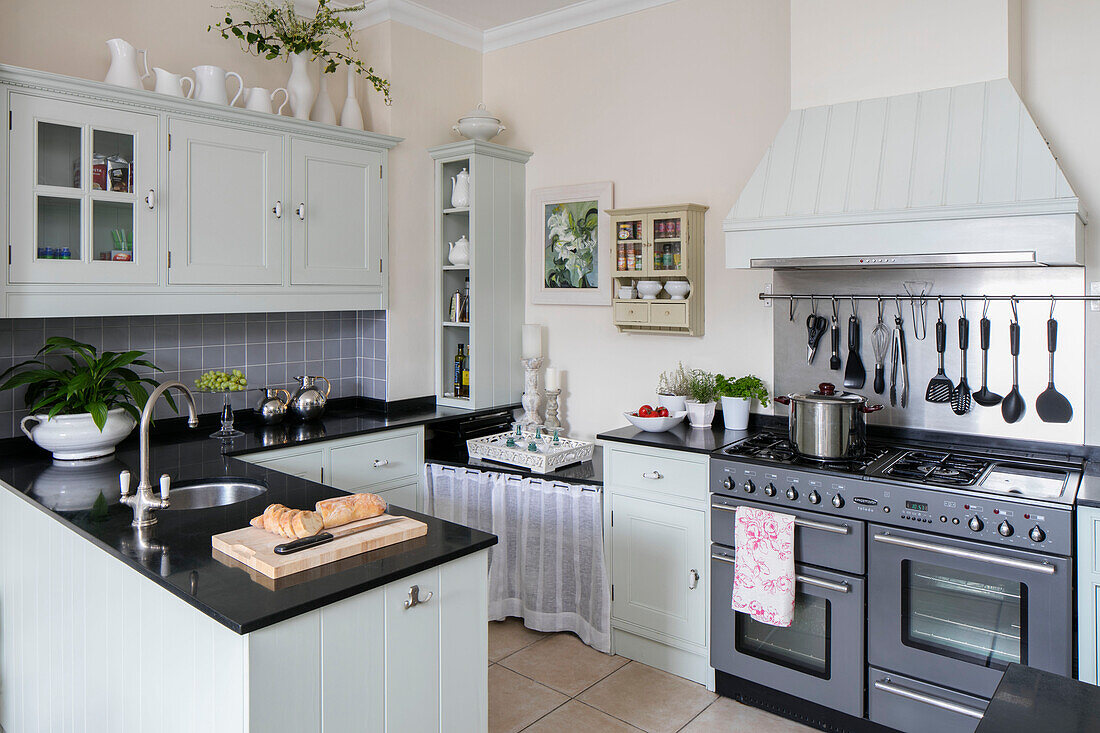 Light green and black fitted kitchen with range oven in West Sussex townhouse UK