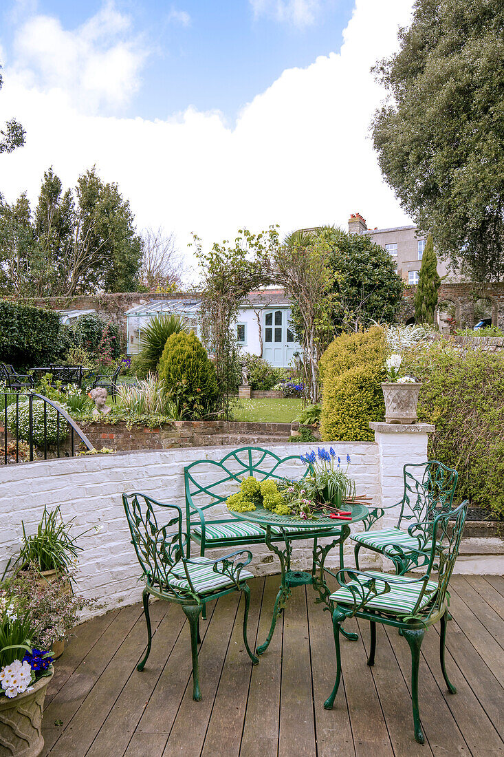 Green table and chairs on terrace in West Sussex townhouse garden UK