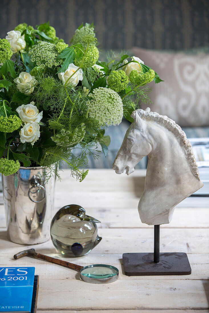 Cut flowers and equestrian head with magnifying lass on coffee table in South London schoolhouse conversion UK