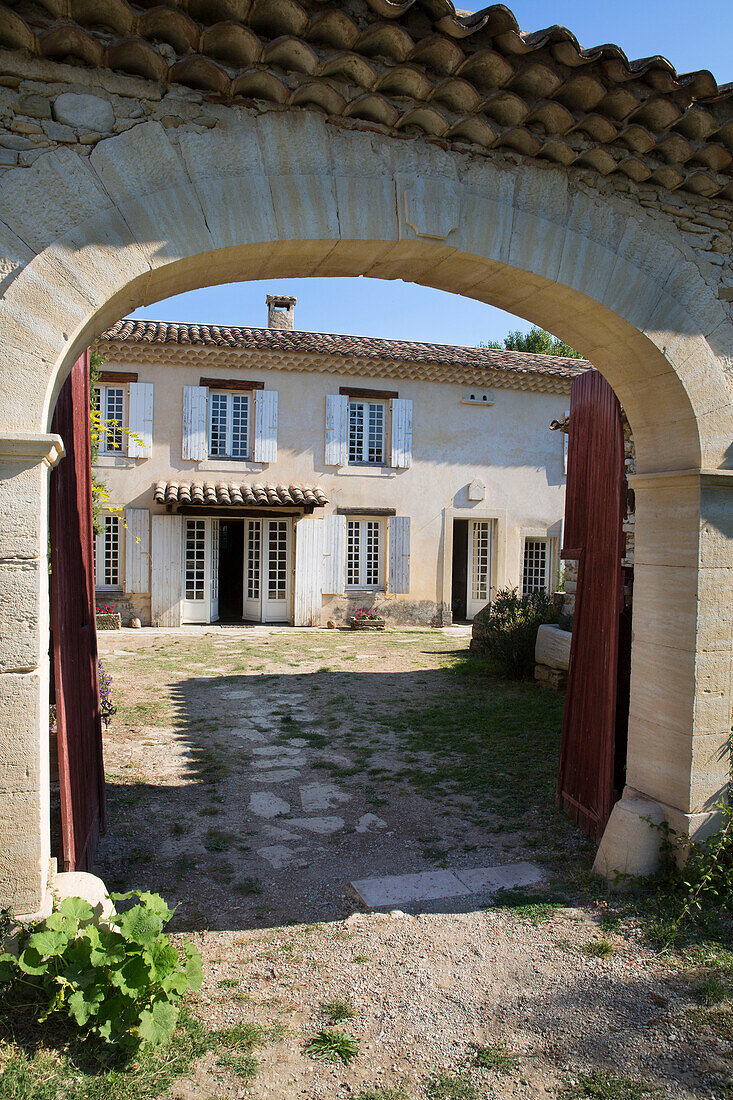 View through arched gateway to courtyard interior of 19th century Provencal farmhouse France
