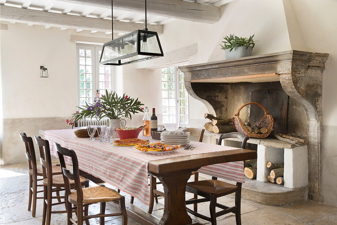 Modern glass lampshade above dining table with original fireplace in 19th century Provencal farmhouse France